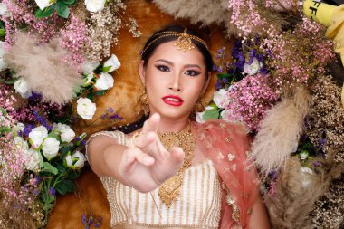 Hint güzeli yüzü mükemmel makyaj gelini, kırmızı pembeli güzel bir kadının portresi geleneksel Hindistan gelinliği, ağır mücevherler ve el ele tutuşmalar, bakış açısı.