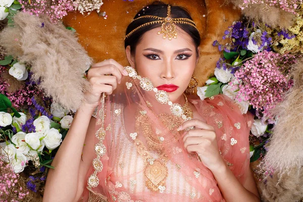 Hint güzeli yüzü mükemmel makyaj gelini, kırmızı pembeli güzel bir kadının portresi geleneksel Hindistan gelinliği, ağır mücevherler ve makyajlı.