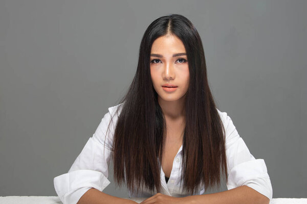 Portrait of Fashion 20s Asian Woman has beautiful black long straight Hair, she wear white shirt look at camera over gray Background isolated copy space