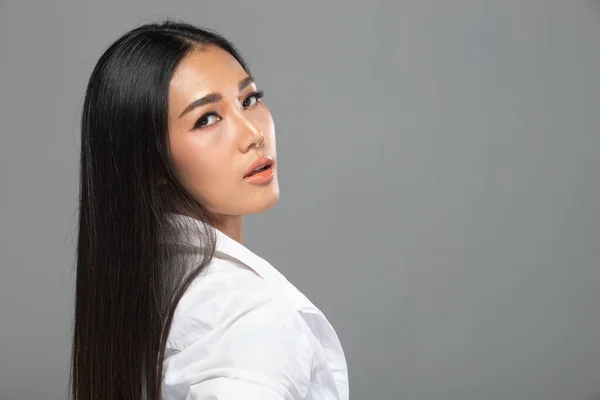 ファッションの肖像20年代アジアの女性は 美しい黒の長いストレートの髪を持っています 彼女は灰色の上にカメラで白いシャツを見て着用背景隔離されたコピースペース — ストック写真