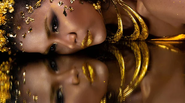 Moda 20 'li yaşlardaki Asyalı kadının portresi fırçasında güzel bir makyaj sanatçısı, yüzünde şık bir altın yaprak ile süslüyor ve aynayı yansıtıyor, boşluğu kopyalıyor.