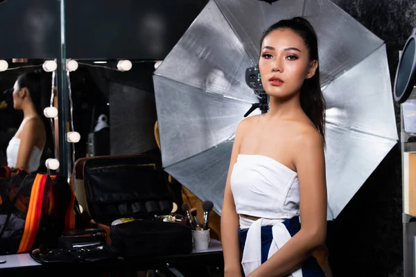 Moda 20 'li yılların Asyalı Kadın portresi güzel moda bir cekete sahip. Süslü stüdyoda ışık ve ekipmanla dergi çekmek için güçlü pozlar veriyor.