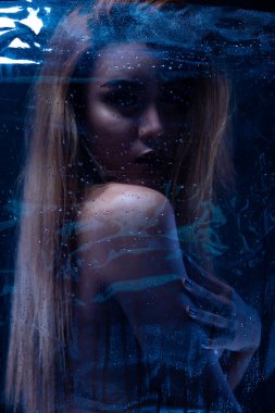 Seksi, çıplak bir kadın. Çıplak, şehvetli, güzel kız. Asyalı kadın erotik pozlar. Banyo banyosunda hafif gölge ve siluet hissi uyandırıyor. Karanlık arka planda cam buhar.