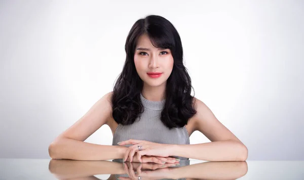 20多岁的亚洲女人看着相机拍照 把手放在镜面桌子上 白色背景隔离复制空间 — 图库照片