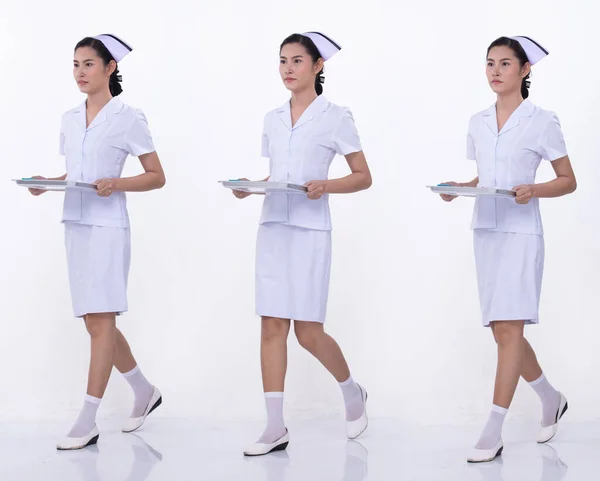 全长20多岁的亚洲妇女身穿白色护士制服和鞋子 女的拿着托盘 在白色的背景上走着多种风格 — 图库照片