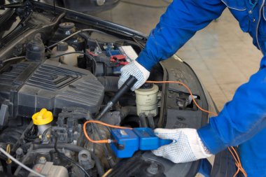 Benzin istasyonunda araba tamiri. Motorda basınç kontrolü. Profesyonel bir tamircinin elleri bir araç tutar..