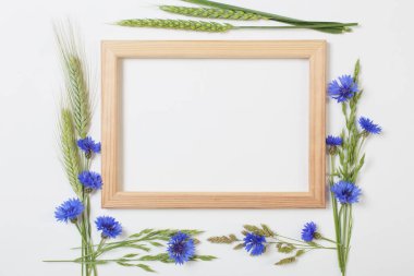 Beyaz arka planda ahşap çerçeveli mavi çiçek ve tahıllar