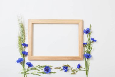 Beyaz arka planda ahşap çerçeveli mavi çiçek ve tahıllar