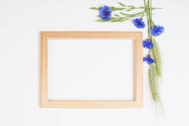 Beyaz arka planda ahşap çerçeveli mavi çiçek ve tahıllar