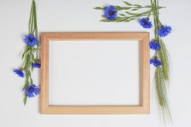 Beyaz arka planda ahşap çerçeveli mavi çiçek ve tahıllar