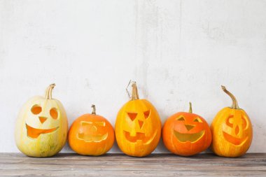 Cadılar Bayramı balkabakları ahşap masada arka planda eski beyaz duvarda