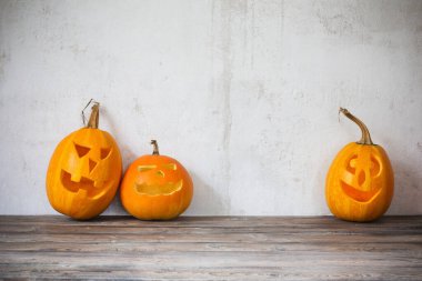 Cadılar Bayramı balkabakları ahşap masada arka planda eski beyaz duvarda