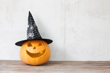 Ahşap masada siyah şapkalı Cadılar Bayramı kabağı