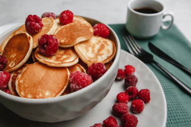Modaya uygun ev yapımı mini krep, ahududu ve beyaz bir masada kahve. Yukarıdan manzara. Yan görüş. Metin için boşluk