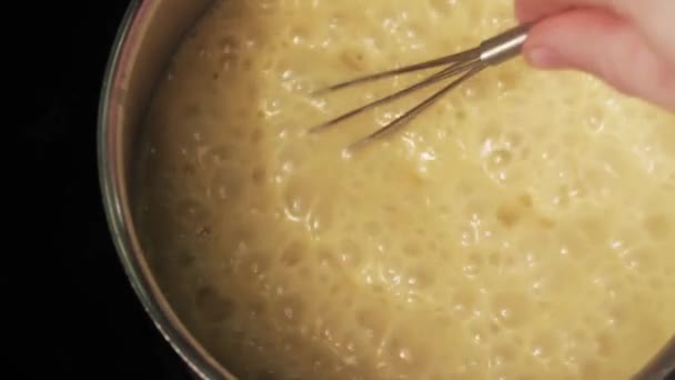 TOP VIEW of stirring with a whisk boiling yellow cream soup in a saucepan — Stock Footage TOP VIEW of stirring with a whisk boiling yellow cream soup in a saucepan Royalty Free Stock Video