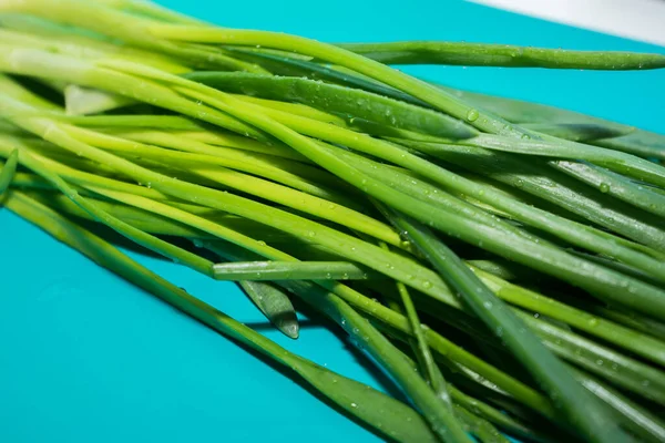 Mencuci bawang hijau yang basah di papan biru. — Stok Foto