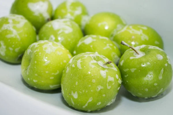 Washing fruit. Soapy green apples in the sink.