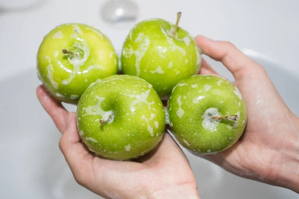 Lavando frutas. A rapariga lava maçãs. Mãos e maçã verde sabão — Fotografia de Stock