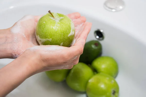 씻는 과일. 손 과 비눗물 이 많은 녹색 사과 스톡 이미지