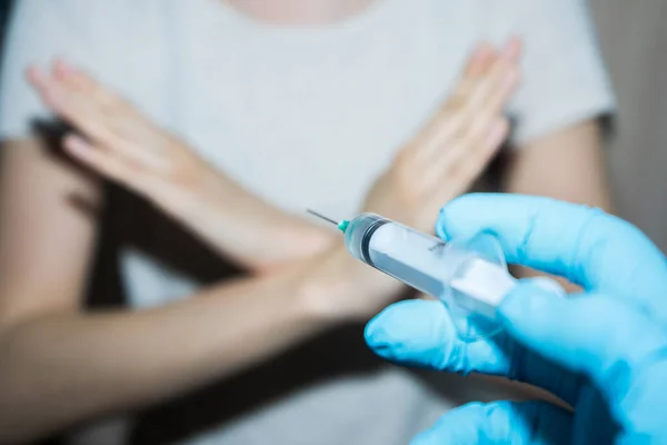 Stop vaccinaties. Een injectiespuit in de hand van de arts en een patiënt zegt nee. — Stockfoto