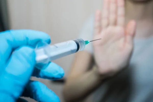 Stop vaccinations. A syringe in the doctor hand and a patient says no.