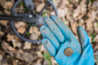 Lastik eldivenli bir kazıcı arkeolog pahalı bir tarihi para buldu.