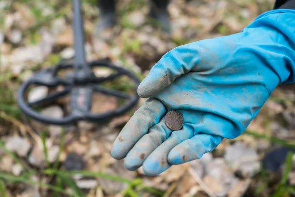 벌목꾼의 손에서 오래 된 동전을 발견 했어. 고무 장갑낀 가난 한 사람 이 동전을 발견 했습니다 — 스톡 사진