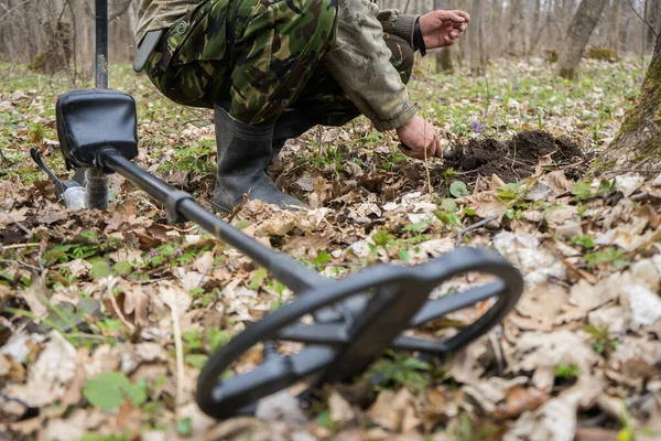 Detector de metais na floresta e um homem a cavar moedas. Procurar moedas ou metais antigos — Fotografia de Stock