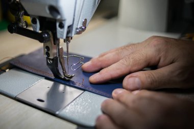 Bir adam dikiş makinesinde deriden dikiş diker. Eller ve dikiş.. 