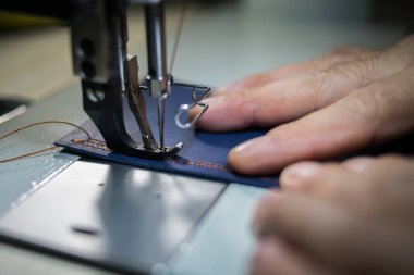 Bir adam dikiş makinesinde deriden dikiş diker. Eller ve dikiş.. 