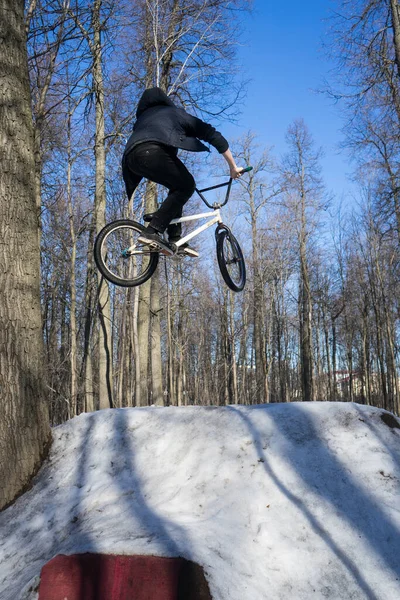 Bmx rider hace un truco de salto de tierra en el invierno. Moto azotar en bmx — Foto de Stock