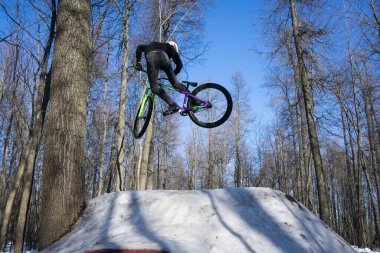Dağ bisikletçisi kışın çamurdan atlama numarası yapar. Motosikletli Moto.