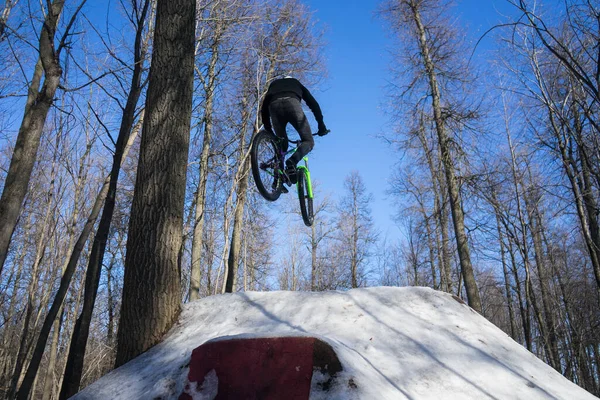 guy jumps on a springboard on a bicycle in winter. winter dirt jumping