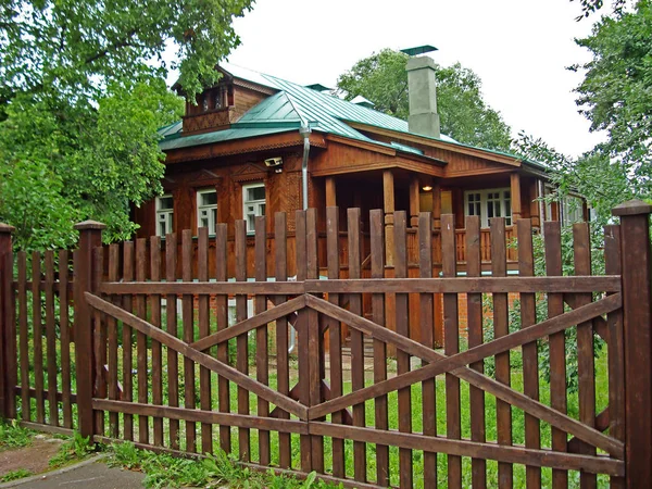 Stary drewniany dom z zielony dach i brązowy ogrodzenia. — Zdjęcie stockowe