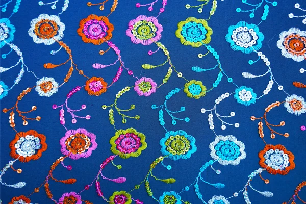 Blue fabric texture with floral embroidery and sequins. — Stock Photo, Image