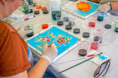 Bir kadın çiçek ipek kumaş üzerine çizmek öğrenir.