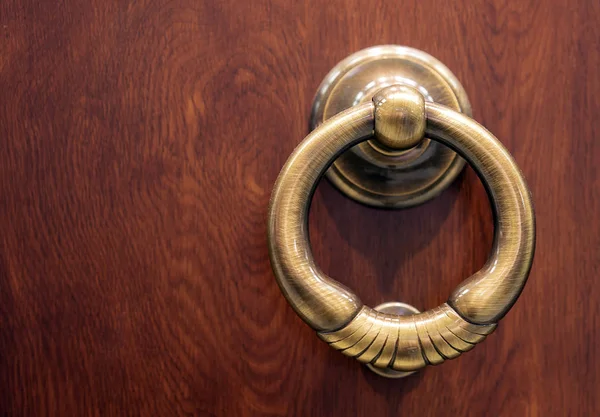The round handle of a door on a brown background.