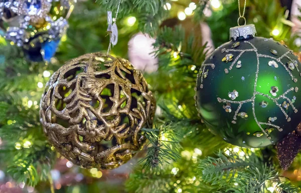 Bola de ouro de ornamento com aberturas em um ramo de uma árvore de Natal. Fundo de Natal . — Fotografia de Stock