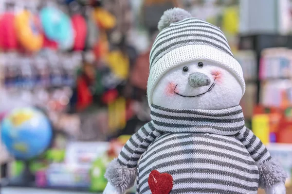 Plyšová hračka s úsměvem sněhulák v pruhovaná čepice a svetry. — Stock fotografie