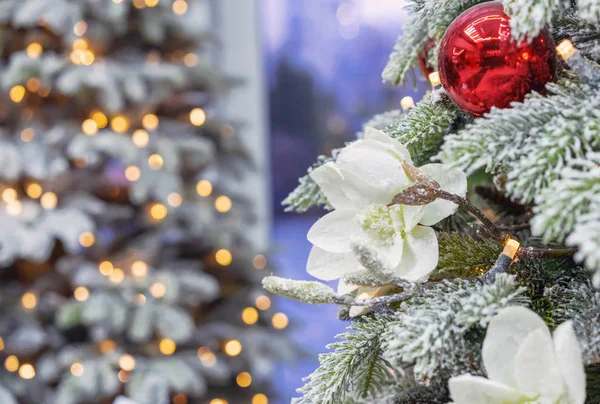 Schneebedeckter Weihnachtsbaum mit Dekorationen auf dem Hintergrund mit Bokeh. — Stockfoto