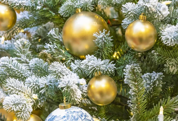 Goldene Kugeln und ein Kranz auf einem verschneiten Weihnachtsbaum. — Stockfoto