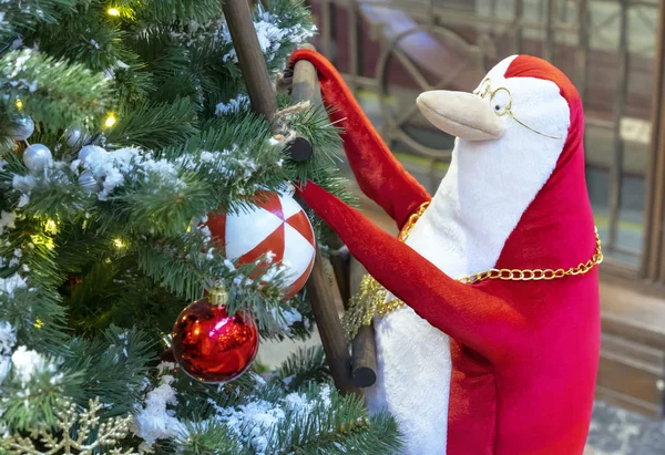 Kırmızı ve beyaz penguen Noel ağacına merdivenlerden tırmanıyor. — Stok fotoğraf
