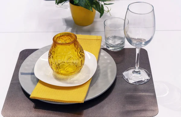 Желтый стеклянный подсвечник на белом тарелке и желтое полотенце . — стоковое фото