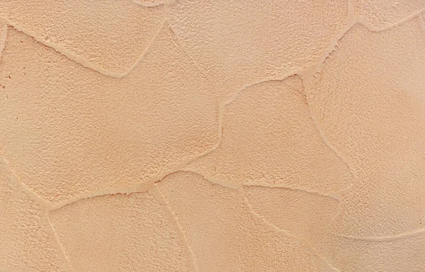 Texture of beige decorative plaster on the wall in the interior of the room.