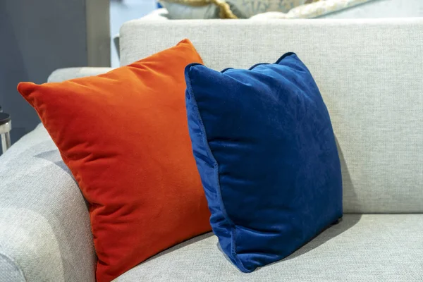 Orange and blue decorative pillows on a beige sofa.