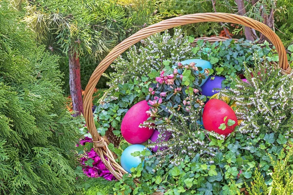 Цветные пасхальные яйца в плетеной корзине на естественном фоне . — стоковое фото