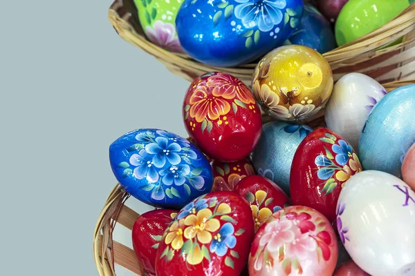 Цветные пасхальные яйца в плетеной корзине на сером фоне . — стоковое фото