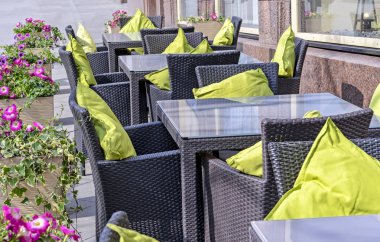 Hasır mobilya ve yeşil yastıklar ile rahat açık kafe.