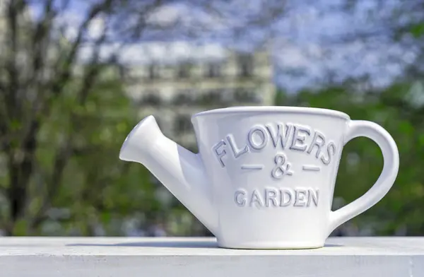 Branco de cerâmica regar lata para regar flores e plantas no fundo da primavera . — Fotografia de Stock