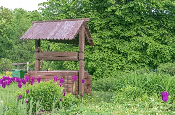 Wooden well in the village. Wooden well on the background of green foliage.